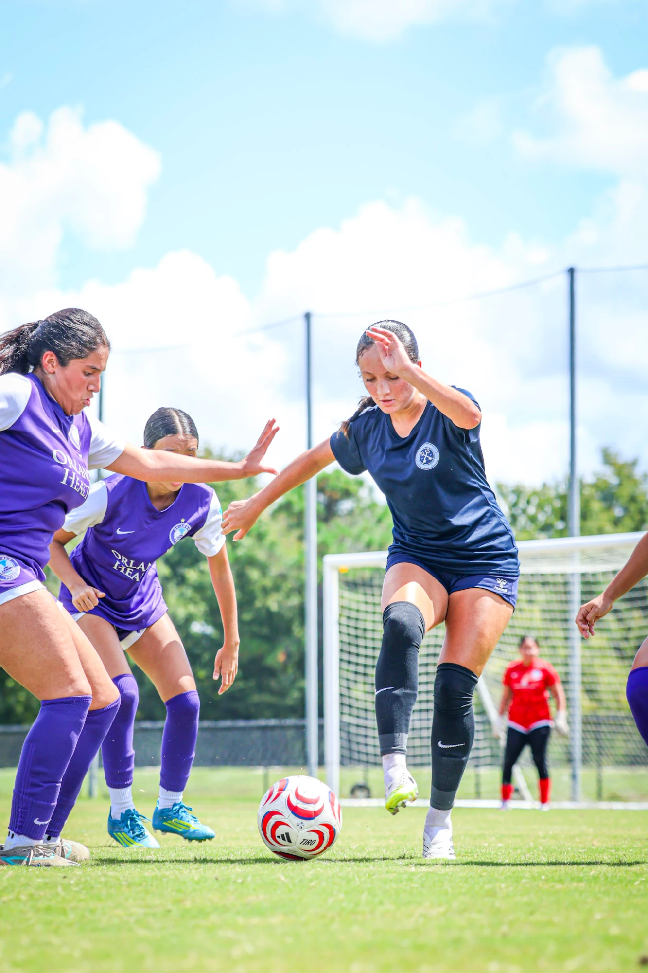 Soccer player dribbling between two defenders
